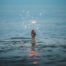 person submerged on body of water holding sparkler - geothermal heat